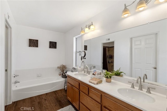 full bathroom with a sink, a garden tub, wood finished floors, and double vanity