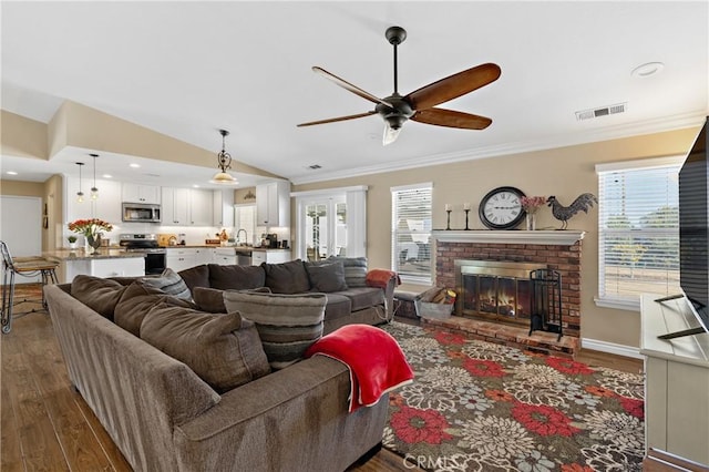 living area featuring visible vents, plenty of natural light, dark wood-type flooring, and a ceiling fan