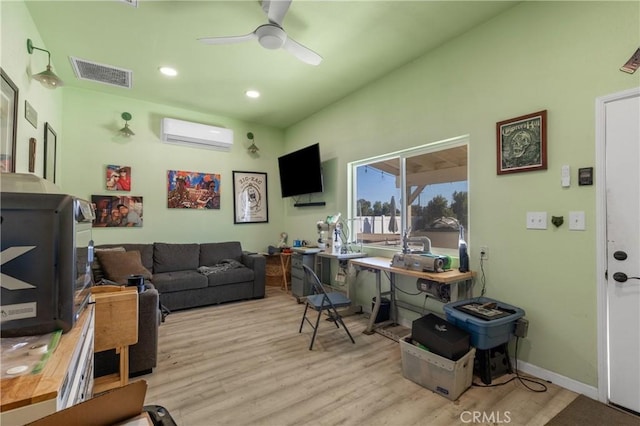 office with light wood-type flooring, visible vents, a ceiling fan, a wall mounted AC, and baseboards