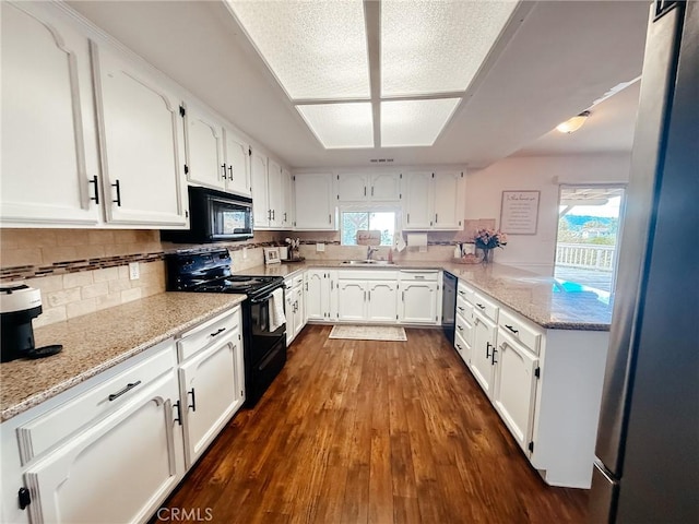 kitchen with tasteful backsplash, dark wood-style floors, light stone countertops, black appliances, and white cabinetry