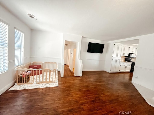 unfurnished bedroom with dark wood-style flooring, visible vents, and baseboards