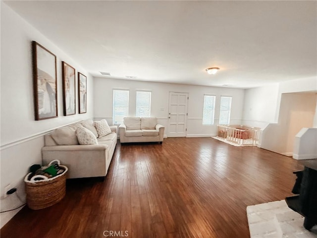 living room with dark wood-type flooring, plenty of natural light, visible vents, and baseboards