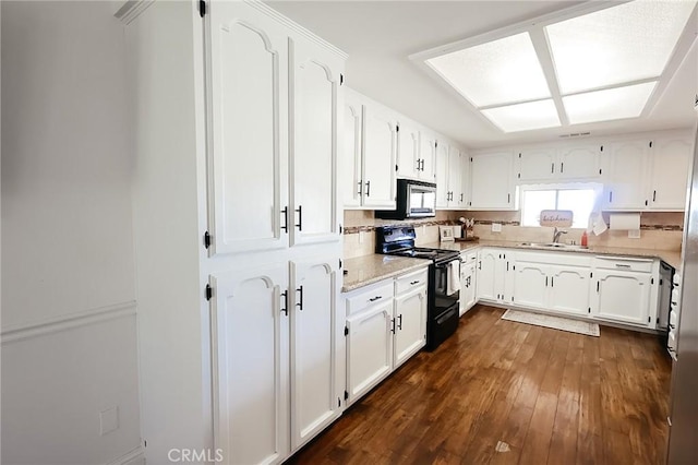 kitchen featuring stainless steel microwave, a sink, white cabinetry, and black electric range oven