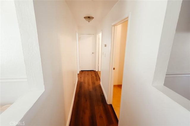 corridor with baseboards and wood finished floors