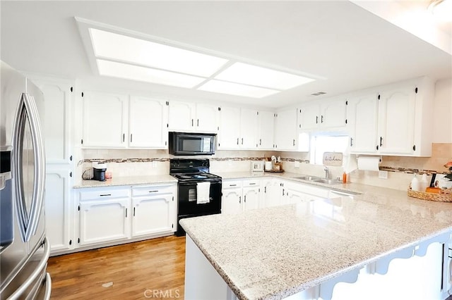 kitchen with a breakfast bar, white cabinets, a peninsula, and black appliances