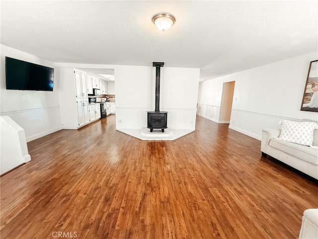 unfurnished living room with a wood stove, baseboards, and wood finished floors