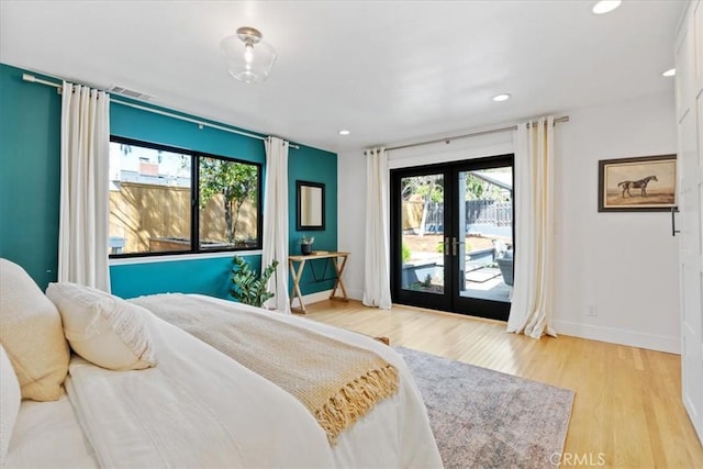 bedroom with access to outside, multiple windows, light wood-style flooring, and french doors