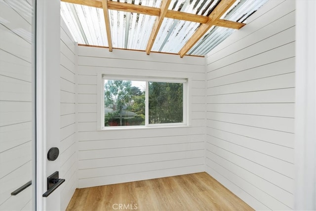 unfurnished room with wooden walls and light wood-style flooring