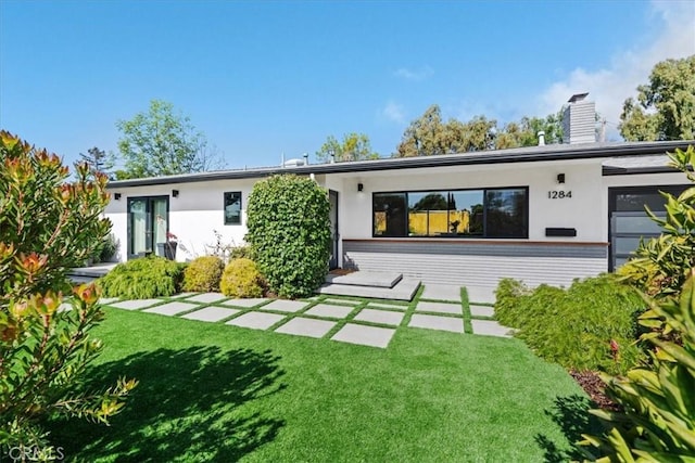 rear view of property featuring stucco siding and a lawn