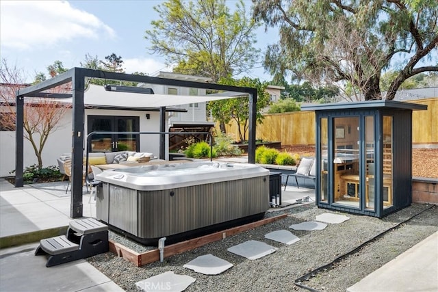 view of patio / terrace with an outbuilding, a hot tub, and fence