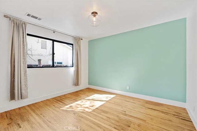 empty room with visible vents, baseboards, and wood finished floors