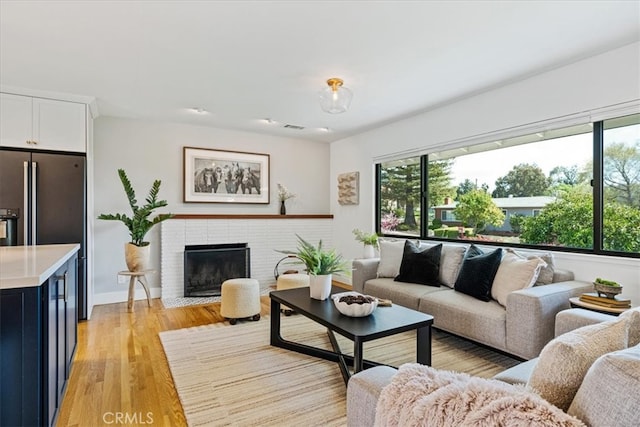 living room featuring visible vents, a fireplace, and light wood-type flooring