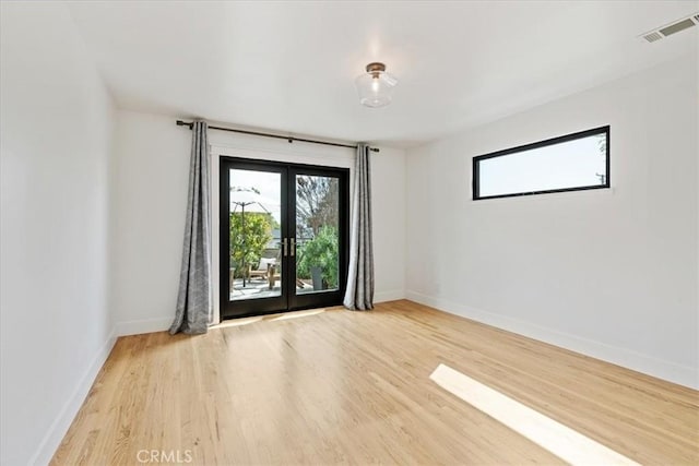 empty room with visible vents, french doors, baseboards, and wood finished floors