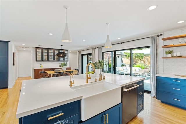 kitchen featuring light wood finished floors, light countertops, recessed lighting, blue cabinets, and a sink