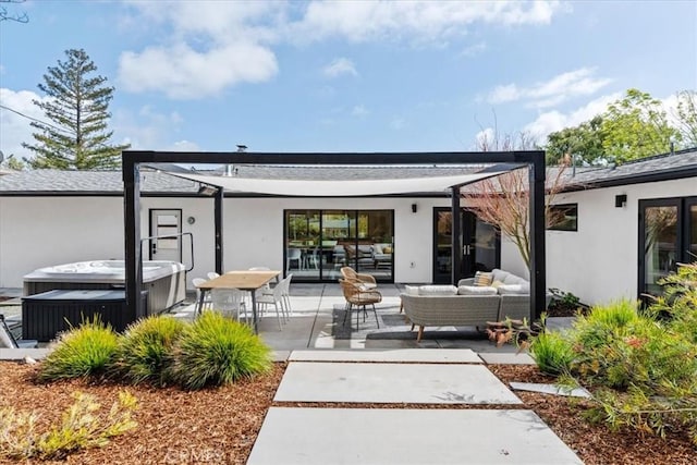 rear view of property featuring an outdoor living space, a patio area, stucco siding, and a hot tub