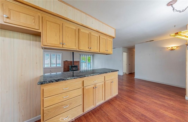 kitchen with dark stone countertops, light brown cabinets, baseboards, and wood finished floors