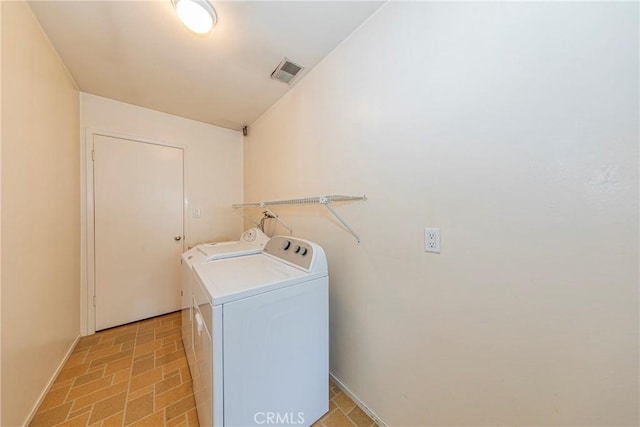 laundry area featuring laundry area, washer and clothes dryer, brick floor, and visible vents