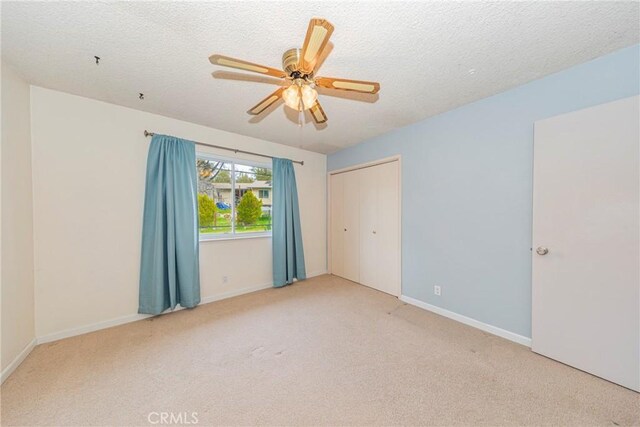 spare room featuring a textured ceiling, carpet floors, ceiling fan, and baseboards