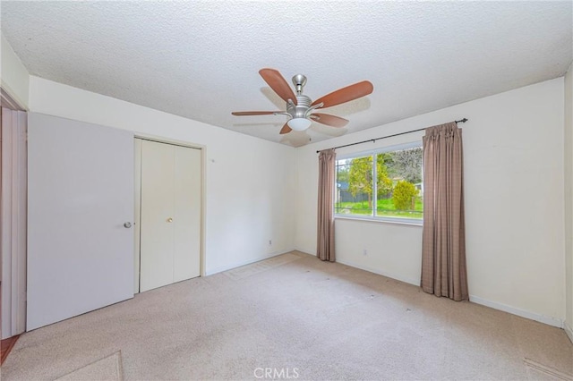 unfurnished bedroom with a closet, a textured ceiling, and light colored carpet