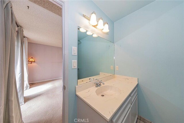 bathroom featuring baseboards, a textured ceiling, and vanity