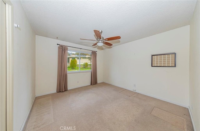 empty room featuring a ceiling fan, a textured ceiling, and light colored carpet