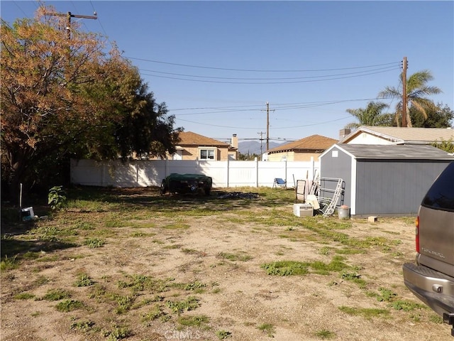 view of yard with a shed, a fenced backyard, and an outbuilding
