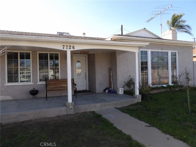 exterior space featuring a porch, a front lawn, and stucco siding