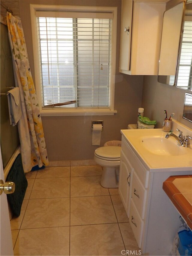 bathroom with curtained shower, vanity, toilet, and tile patterned floors