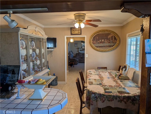 dining area with baseboards, a ceiling fan, crown molding, and light tile patterned flooring