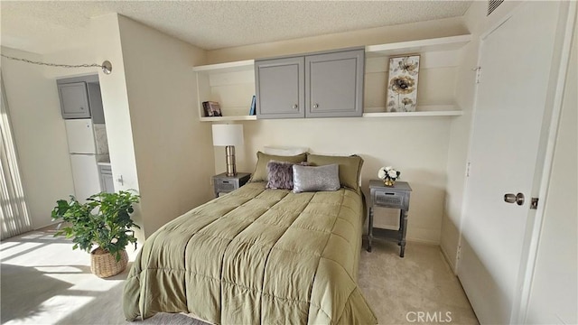 bedroom with visible vents, light carpet, a textured ceiling, and freestanding refrigerator