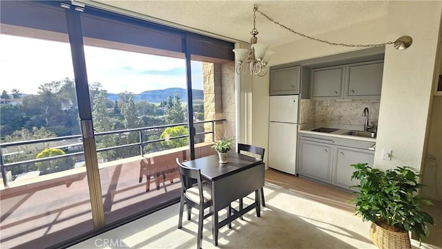 dining room featuring a wall of windows, a mountain view, a textured ceiling, and an inviting chandelier