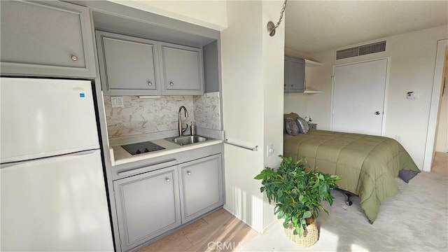 kitchen featuring a sink, visible vents, gray cabinets, and freestanding refrigerator