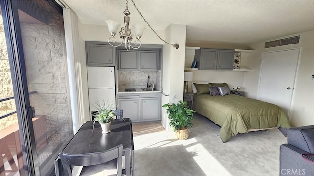 bedroom featuring a chandelier, visible vents, freestanding refrigerator, and a textured ceiling