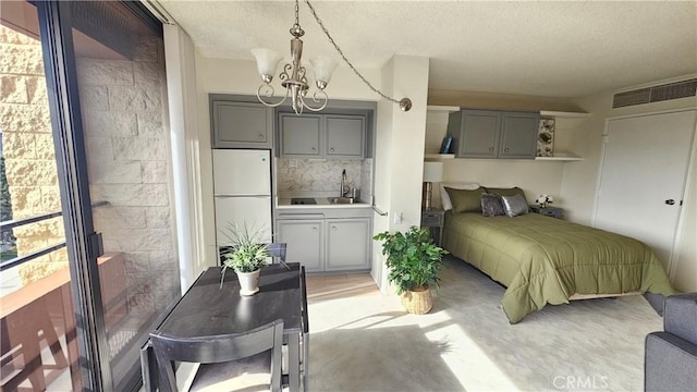 bedroom with visible vents, a sink, a textured ceiling, freestanding refrigerator, and an inviting chandelier