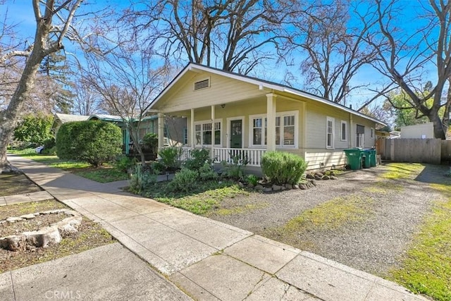 bungalow-style home with fence, covered porch, and driveway