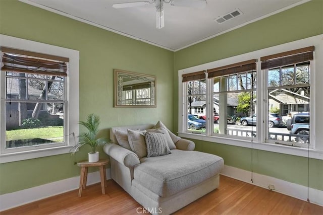 sitting room featuring visible vents, baseboards, wood finished floors, and ornamental molding