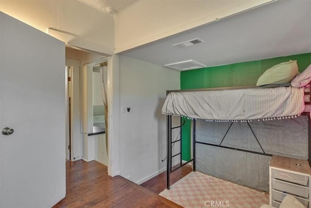 bedroom featuring visible vents, attic access, and wood finished floors