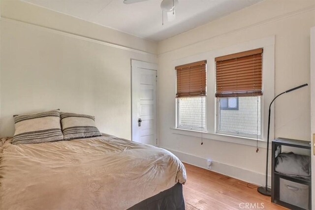 bedroom with ceiling fan, light wood-type flooring, and baseboards