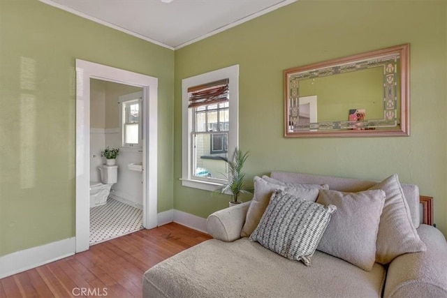 bedroom with hardwood / wood-style floors, crown molding, baseboards, and ensuite bathroom