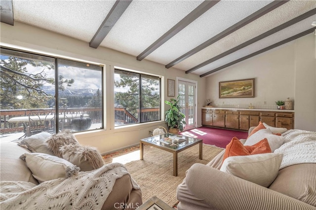 living area with lofted ceiling with beams, dark colored carpet, and a textured ceiling