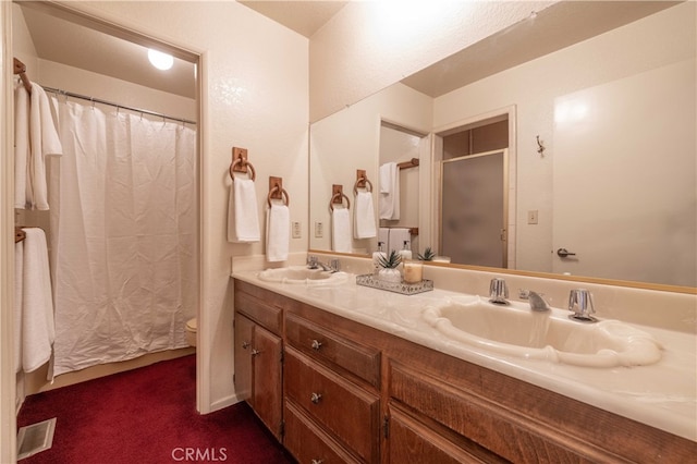 full bath featuring double vanity, curtained shower, a sink, and toilet