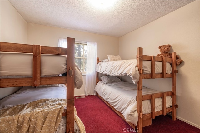 bedroom featuring visible vents, a textured ceiling, baseboards, and carpet flooring