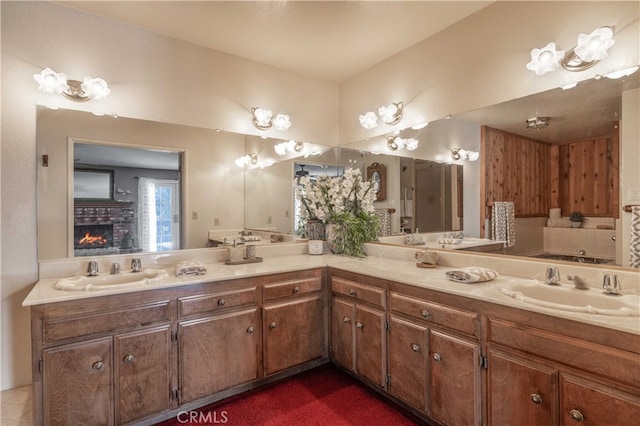 bathroom featuring double vanity, a fireplace, and a sink