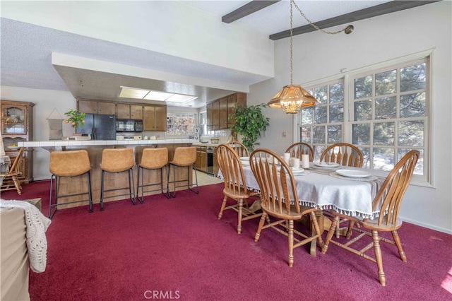 dining room featuring beamed ceiling and carpet flooring