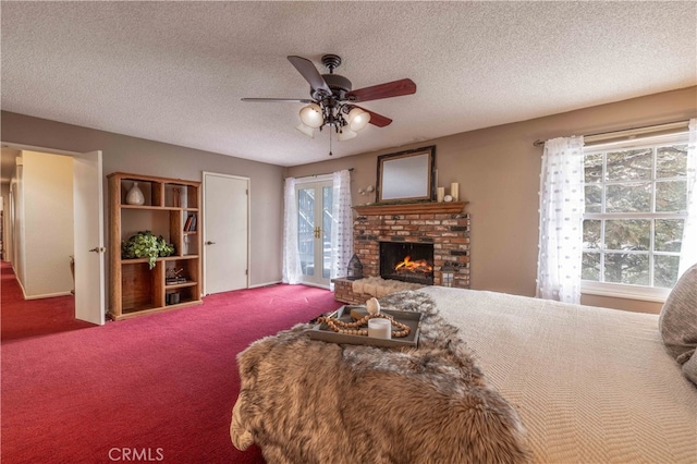 carpeted bedroom featuring a textured ceiling, access to outside, a fireplace, and a ceiling fan