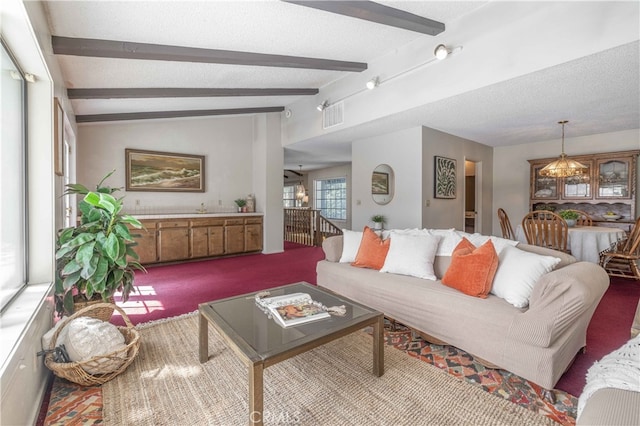 carpeted living area with vaulted ceiling with beams, an inviting chandelier, visible vents, and a textured ceiling