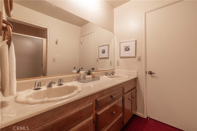 bathroom with double vanity, a shower stall, and a sink