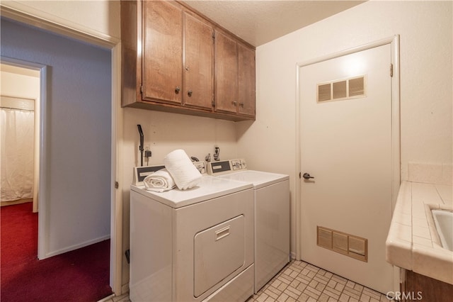 washroom featuring cabinet space, visible vents, and washer and dryer