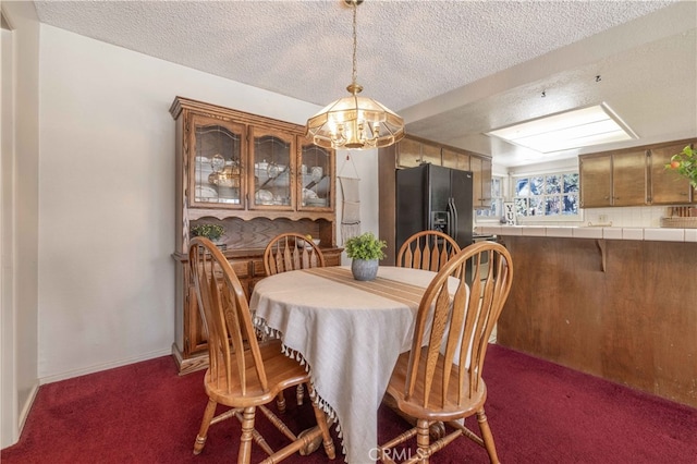 dining area with dark colored carpet, a textured ceiling, and baseboards