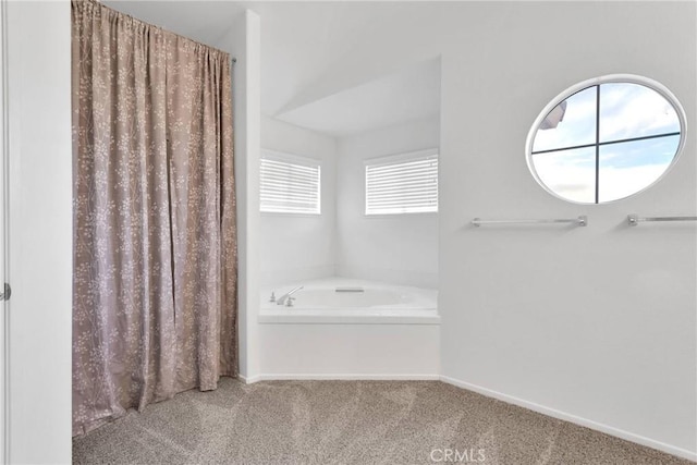 bathroom featuring a garden tub and baseboards